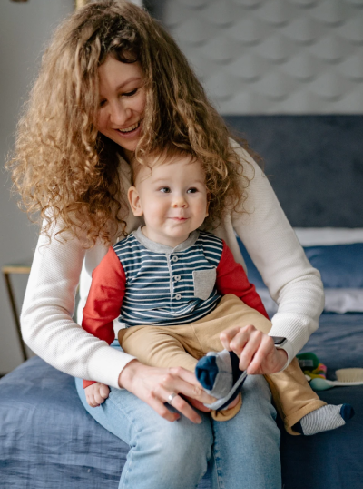 mom holding baby Mother puts on sons shoes
